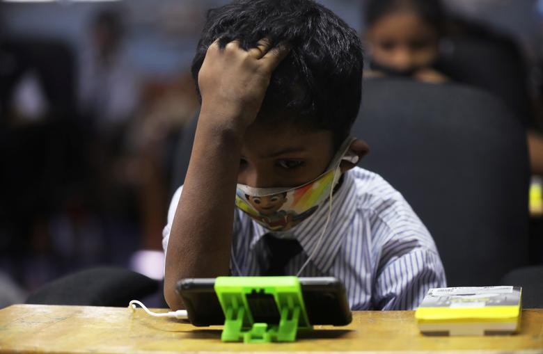 A student watches an online lecture on a mobile phone, inside a digital mobile education library, initiated to provide mobile phones to chidren who have no access to them for their education classes amidst the spread of the coronavirus disease (COVID-19) in Mumbai, India, October 16, 2020. REUTERS/Francis Mascarenhas